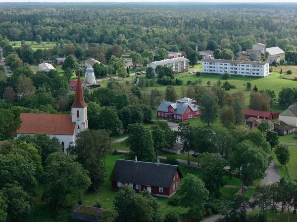 Mustjala, Estonya-12 Eylül 2025: Küçük bir kırsal köyün özünü yakalayan hava manzarası, bir kilise, geleneksel evler, bereketli alanlar ve sık orman manzarası ortaya çıkarıyor.