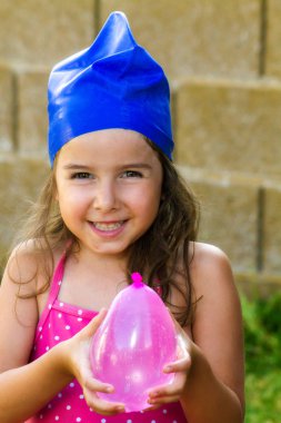 Bir çok güzel, Genç kız mavi yüzme şapkası ve tutan bir pembe balon su. O tatlı ve muzip bir gülümseme vardır. Boşaltmak vardır. Eğlenceli yaz görüntü.