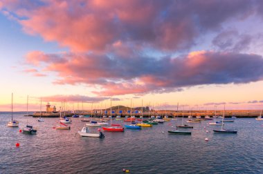 Howth, Dublin, İrlanda muhteşem gün batımı. Howth deniz feneri ve ön, renkli deniz araçları üzerinden görünüm.