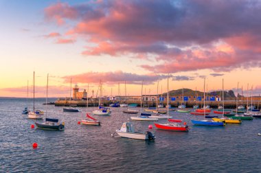 Howth, Dublin, İrlanda muhteşem gün batımı. Howth deniz feneri ve ön, renkli deniz araçları üzerinden görünüm.