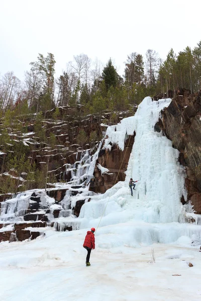 climbers train on a glacier in the mountains, climber climbs the glacier on a safety rope with an ice pick and a helmet, climbers climb in turn on the icefall using an ice pick