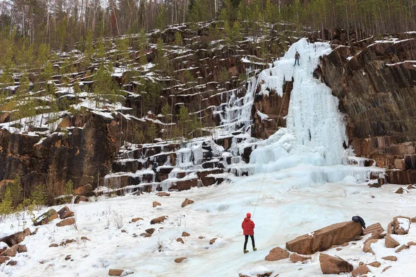 climbers train on a glacier in the mountains, climber climbs the glacier on a safety rope with an ice pick and a helmet, climbers climb in turn on the icefall using an ice pick