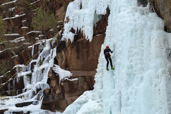 climbers train on a glacier in the mountains, climber climbs the glacier on a safety rope with an ice pick and a helmet, climbers climb in turn on the icefall using an ice pick