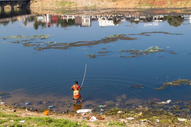 Kirli bir nehirde balık tutan bir kadın, Asya 'daki rezervlerin ekolojisi sorunu.