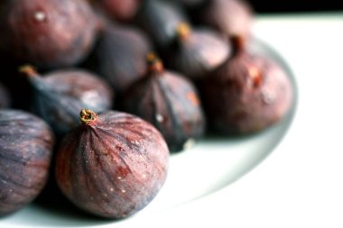  Beyaz bir tabakta taze, olgun incirlerin profesyonel yakın çekimi. Sığ bir alan derinliği var. Superfood ve beslenme üzerine bir sağlık dergisi için ideal..