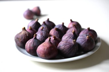 Yumuşak odaklı, beyaz bir tabakta olgun incir, rafine bir yemek kitabı için mükemmel, gurme bir tatlı tarifi, ya da yaşam tarzı özelliği.