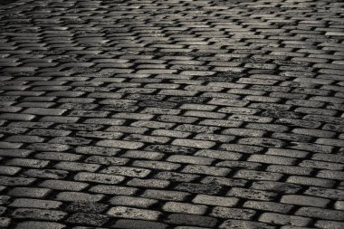 Bir kaldırım taşı döşeli yoldan güneş ışığı yansıtır