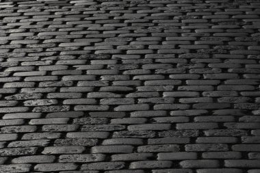 Bir kaldırım taşı döşeli yoldan güneş ışığı yansıtır