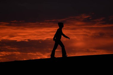 Bir tepenin arka planda gökyüzü ile bir insan silüeti gezer