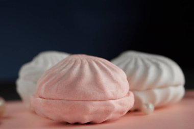 Yakın çekim ev yapımı zephyr bir pembe pastel tablo ve koyu mavi arka plan görüntüsünü.