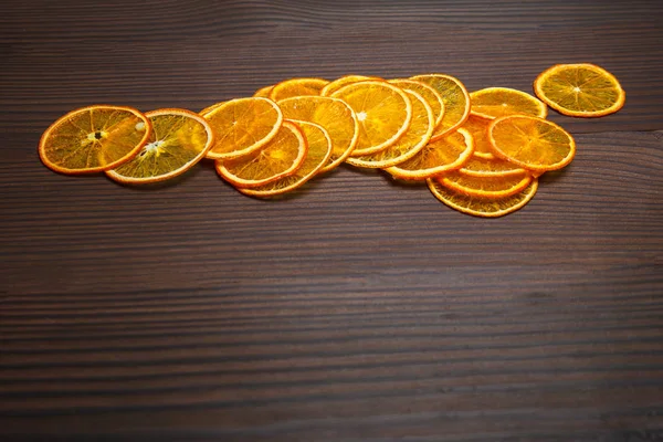 Fruit chips. Bright dried slices of orange on a dark wooden background. space fot text