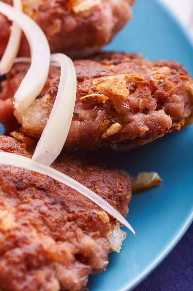 Buffet served in a hearty breakfast, lunch and dinner. Appetizing meat cutlet with fresh onions on a blue plate. Cutlets from minced meat cooked in frying pan, on grill, in oven, in double boiler.