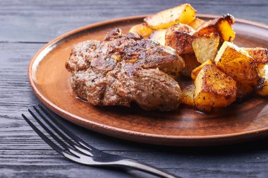 Bir büyük kil plaka üzerinde kızarmış et iştah açıcı parçası. Garnitür olarak gevrek kabuk ile kızarmış patates. Tablolar öğle ve akşam evde, kafede bir restoranda servis edilir.