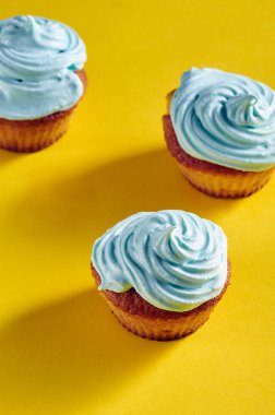Güzel bir mavi krem ile olağandışı cupcakes. Kek mükemmel kapakları protein krem yaptı. Mavi gıda renk ile krem şanti. Sarı-mavi arka plan üzerinde çocuklar için tedavi.