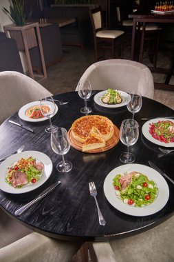 Şef bir kafede lezzetli yemekler çeşitli şık siyah tabloyla restoran. Yemek masası hazır ve özel amaçlı misafirler için. Masanın ortasında içinde peynir kek.