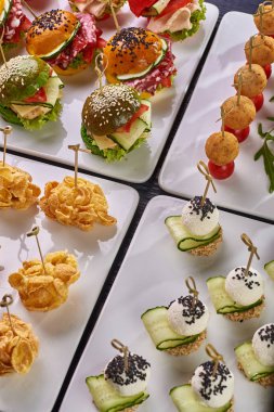 Şenlikli bir tablo, büfe, tüm aile ve arkadaşlar için bir parti için farklı yemek seçenekleri kümesi. Domates, Mısır gevreği, renkli Burger, peynirli çerez salatalık ile topları ile kroket.