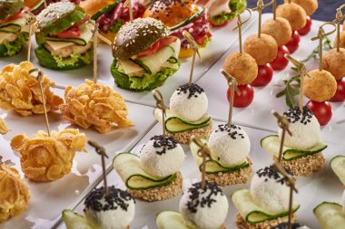 Şenlikli bir tablo, büfe, tüm aile ve arkadaşlar için bir parti için farklı yemek seçenekleri kümesi. Domates, Mısır gevreği, renkli Burger, peynirli çerez salatalık ile topları ile kroket.