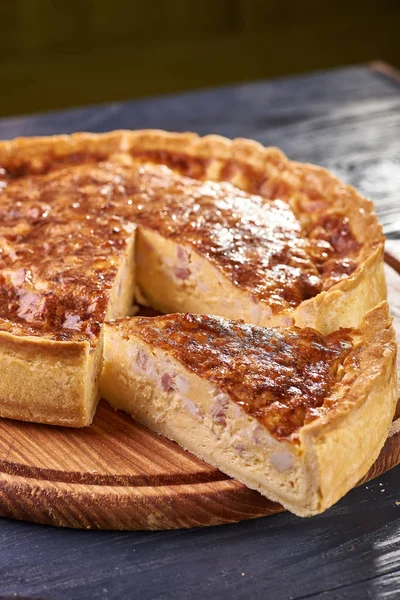 Appetizing cheese cake with sausage, ham. Snack unsweetened cake with crispy cheese crust. An unusual variant of pizza is \