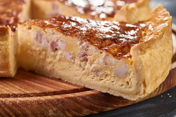 Appetizing cheese cake with sausage, ham. Snack unsweetened cake with crispy cheese crust. An unusual variant of pizza is \