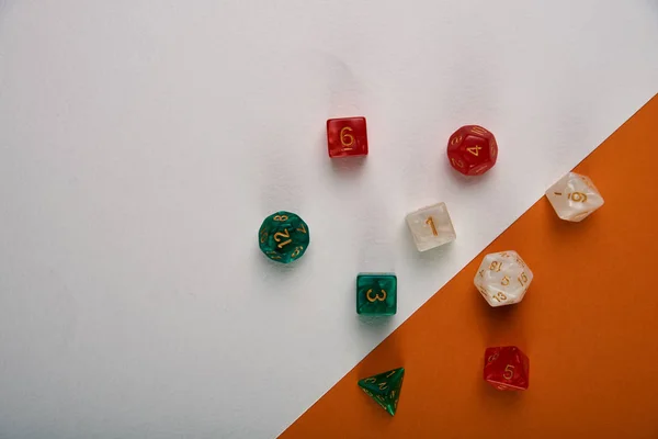 Unusual dice for board games on a two-tone white and orange background, table. Accessories, pebbles, cubes for playing the famous board game \