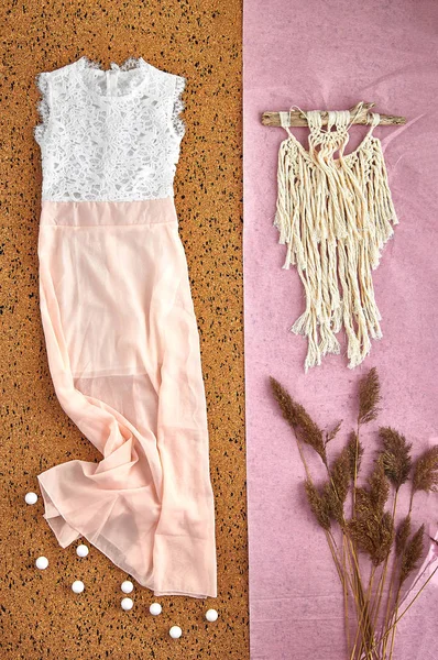 Beautiful unusual outfit presentation for fashion blog, advertising, clothing catalog. Delicate pink dress made of transparent fabric with a white lace bodice. Dream catcher and dry spikelets.