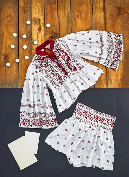 Beautiful unusual outfit presentation for fashion blog, advertising, clothing catalog. Ukrainian, Russian, Belarusian, Slavic, European national costume. Unusual white embroidered top and shorts skirt