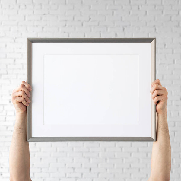 Holding frame mockup. Photo Mockup. Man hands hold frame. For frames and posters design. Frame size 16x12 (40x30cm).