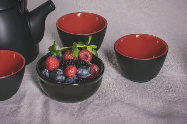 Siyah-kırmızı çilek ile tablo, siyah ve kırmızı bardak çay için öğeleri