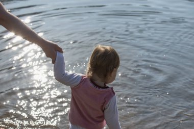 el bir anne güneş altında küçük bir çocuk suya geliyor tutar