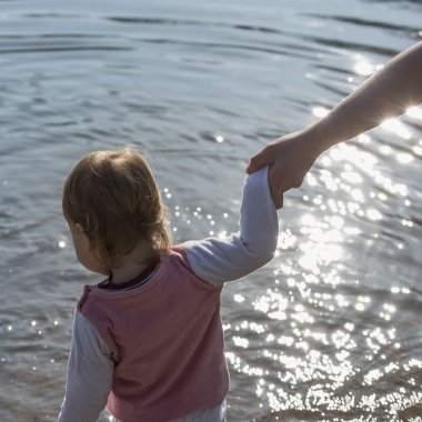 el bir anne güneş altında küçük bir çocuk suya geliyor tutar