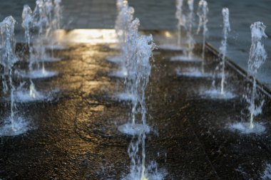 Akşam güneş parlamayı, damla ve sıçraması ile şehir Çeşme bulanık arka plan dokusu