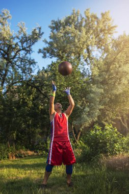Genç atlet açık havada bir top ile spor çalışmaları gerçekleştirir