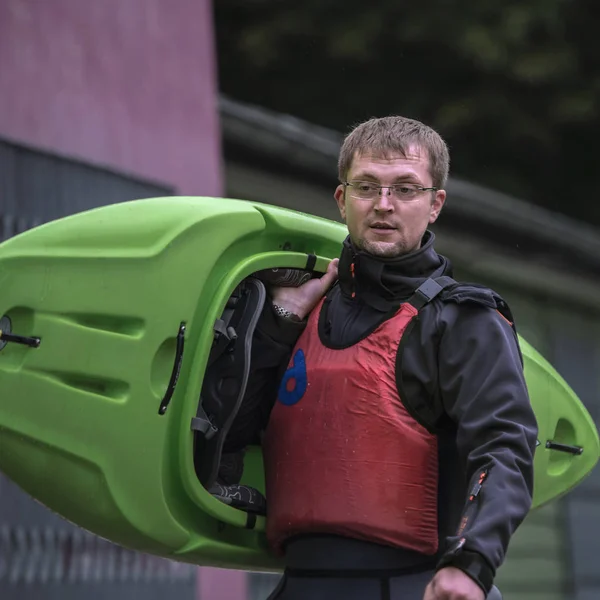 sports man in water sports equipment carries a kayak on his shoulder