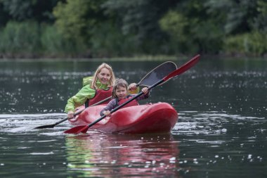 Anne ve kızı eğlenceli ve dostça bir geniş nehir Kano teknede yönetmek