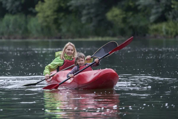 Anne ve kızı eğlenceli ve dostça bir geniş nehir Kano teknede yönetmek