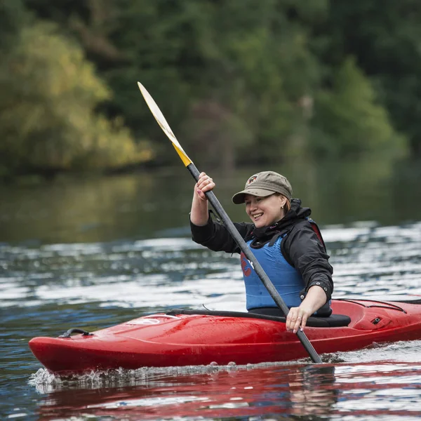 Young blonde girl swims on a sports boat kayak on a beautiful river