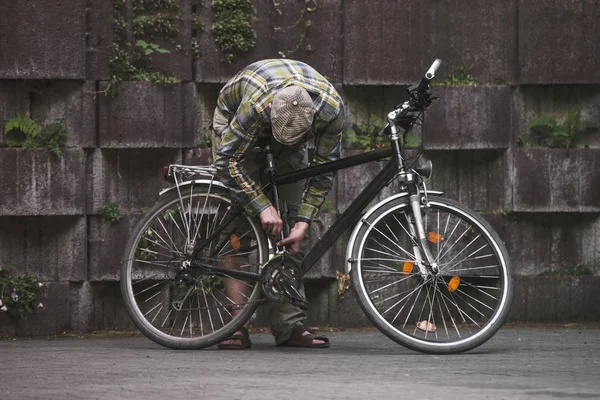 穿格子衫和帽子的男子在旅行前防止旧自行车 — 图库照片