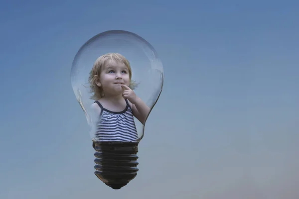 conceptual image of the idea that has come, a little sweet girl is inside the lamp, bringing her finger to her lips and looking thoughtfully into the distance