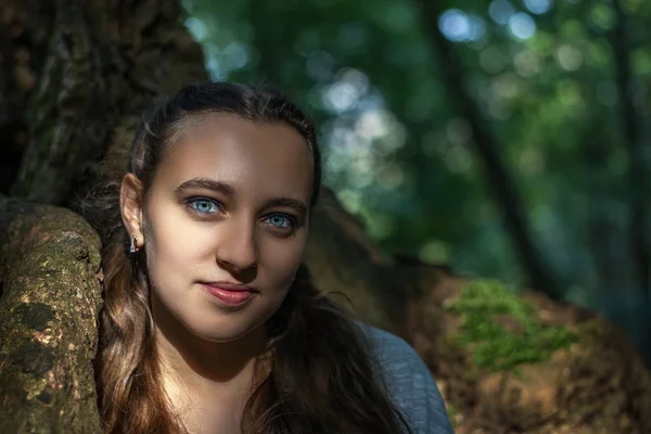一个年轻美丽的黑发与蓝色眼睛在绿色的童话森林的画像 — 图库照片