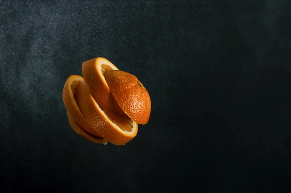 Orange juicy orange fruit cut on several slices on a dark gradie