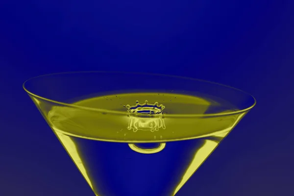 Poslední kapka nápoje spadne do skleničky na Martini, modrá-žlutá GRA — Stock fotografie