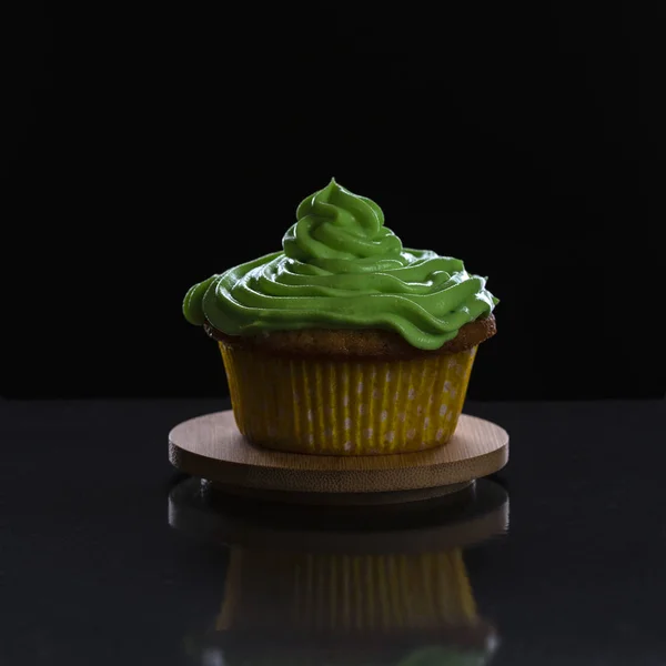 Dolce cupcake fresco decorato con crema verde su uno stand di legno — Foto Stock