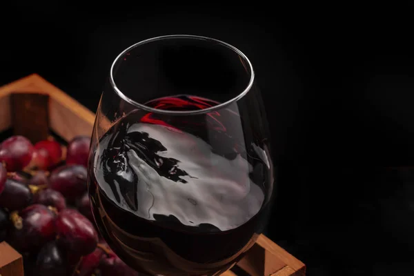 Belle éclaboussure de vin rouge dans un gobelet en verre dans une boîte en bois avec — Photo