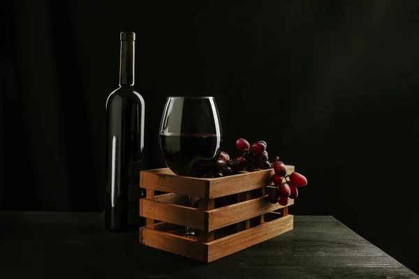 Stilleven van een fles en een glas rode wijn in een houten b — Stockfoto