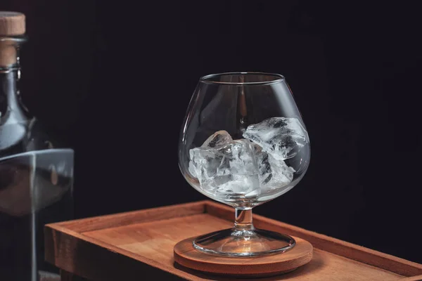 Gelo lascado em um copo de conhaque transparente, em uma caixa de madeira em um — Fotografia de Stock