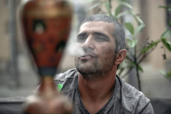 Курильщик кальян выдыхает табачный дым крупным планом в открытом кафе . — стоковое фото