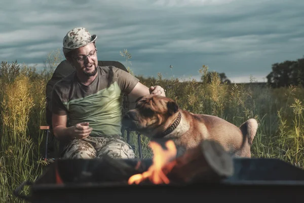 Hombre jugando con un perro Shar Pei al aire libre a la luz del fuego . — Foto de Stock