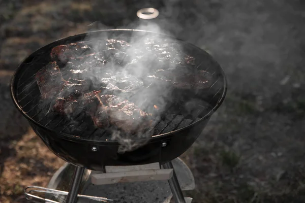 Kött är stekt på en rund grill på kol med rök, en mysig sommar — Stockfoto