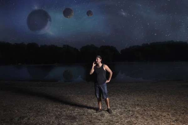 young man in shorts and cap, at night talking on a mobile phone