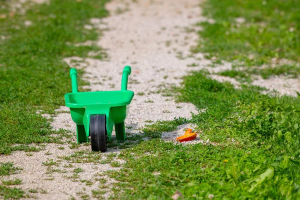 Carretilla de juguete con pala en la hierba, juguete abandonado — Foto de Stock